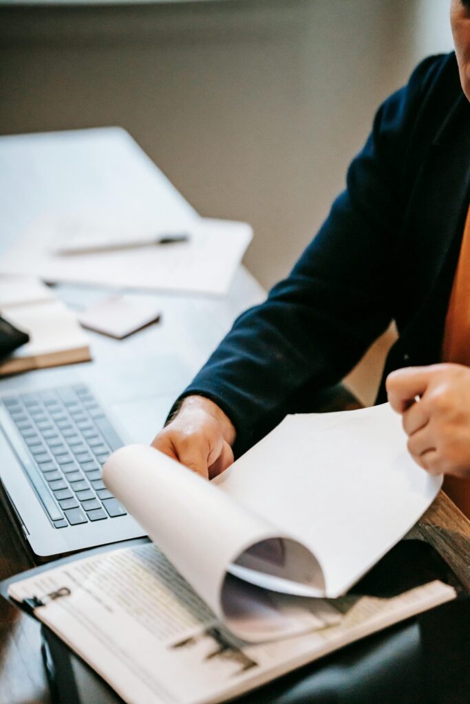 Person reviewing documents with laptop for work analysis.
